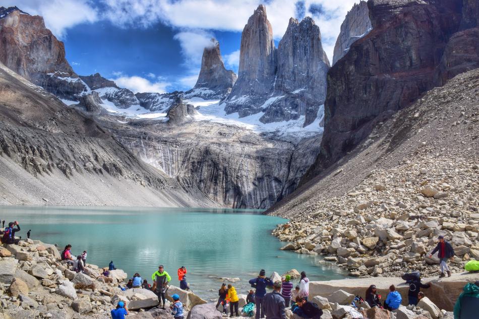 People on the rocks, near the beautiful lake and snowy mountains in Patagonia