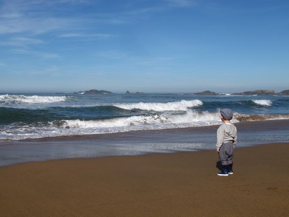 child on the sand near the waves