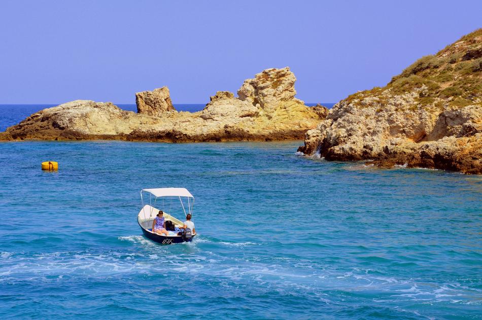 tourists sail on a boat along the mountain range in Puglia