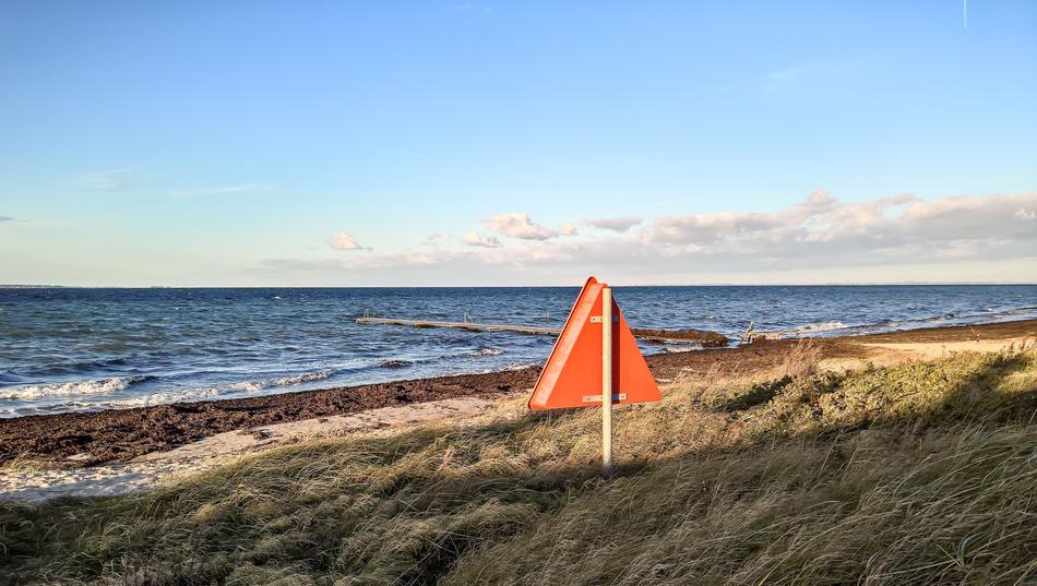 Red shield sign among the plants, on the coast of Baltic Sea in Denmark