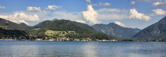lake at the foot of the mountain with green trees under the sky with clouds