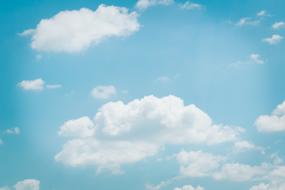 white clouds on a light blue sky with sunbeams