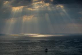 sun rays shining through dark clouds over the ocean