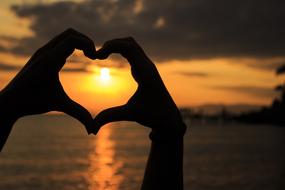 heart from hands on the background of the setting sun