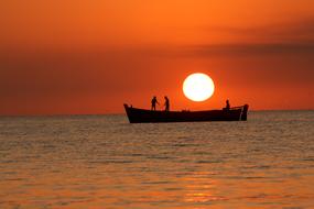 Silhouette of the boat with people, on the sea, at colorful and beautiful sunset