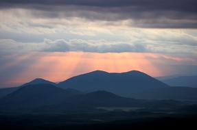 clouds and pink rays over mountains