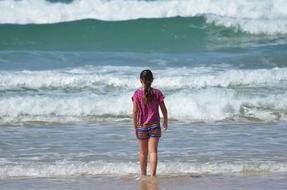 little girl on the beach in the foam waves