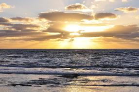Beach of the sea with waves, at colorful sunset among the clouds