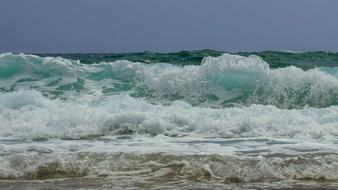 Beautiful beach of the sea, with colorful waves, at blue sky on background