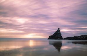 Beautiful rocky shore of the sea, under the colorful and beautiful sunset among the clouds