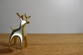 Beautiful, shiny, gold figure of the Christmas deer, on the wooden table