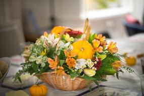 Beautiful and colorful Thanksgiving flowers and pumpkins in wicker basket, in the fall