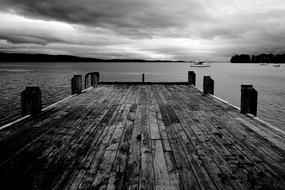 Beautiful, black and white photo of the dock, near the boats, under the clouds