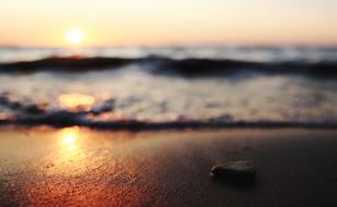 Close-up of the beautiful, shiny beach of the sea with waves, in colorful and beautiful sunset
