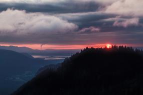 red sun in gray clouds over mountains in switzerland