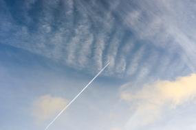 Airplane Chemtrails over blue white clouds