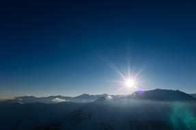 bright sun in the blue clear sky over the mountains