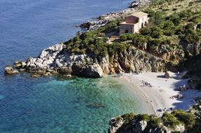 Beautiful, sandy beach and coast with cliffs and building, in Sicily, Italy