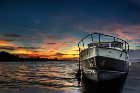 Shiny boat on the water with ripple, at colorful and beautiful sunset with clouds