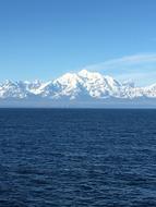 sea with calm water against the backdrop of mountains in the snow