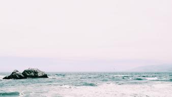 distant view of rocks in ocean in blurred background