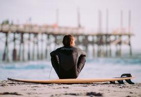 a man sitting on a surfboard on the shore