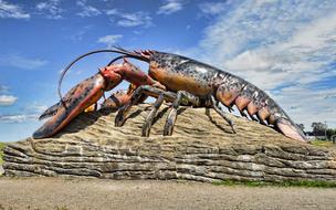 Colorful, shiny sculpture of lobster in Shediac, New Brunswick, Canada, under the blue sky with clouds