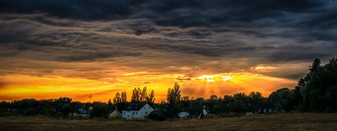 yellow rays in dark clouds over countryside at sunset