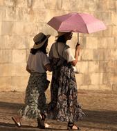 two women under an umbrella are walking down the street