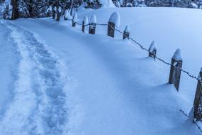 path in the snow near the fence in winter