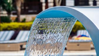 Close-up of the beautiful water fountain on the street of the city, near the colorful plants