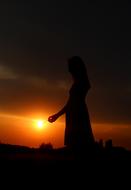 silhouette of a girl against the setting sun at dusk