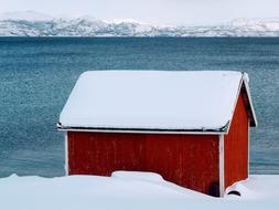 red wooden house near the sea in winter