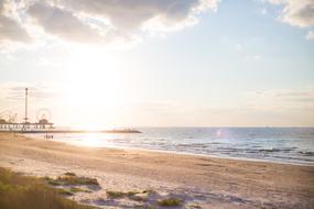 Sandy beach with funpark, in sunlight, under the blue sky with clouds