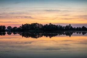 Sunset sky and trees mirroring on Lake