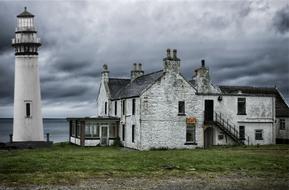 stone house and white lighthouse by the ocean