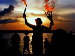 juggler with fire near the water at dusk