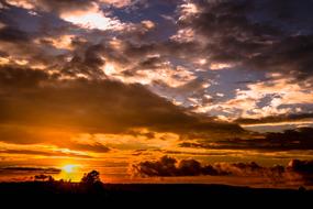 evening sun with clouds over trees at dusk