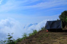 Tent on the beautiful and colorful mountain with green plants, in the blue sky with clouds