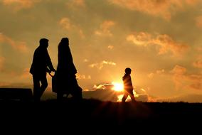 Silhouette of the family, walking on landscape, at colorful and beautiful sunset with clouds