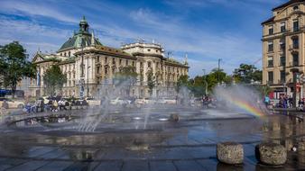 Beautiful landscape of the Charles Square with the fountain with colorful rainbow, in Munich, Germany