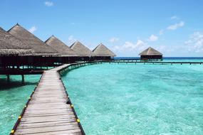 Beautiful pier of the sea, with turquoise water and huts, under the blue sky with clouds