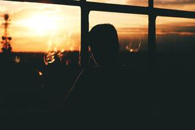 Silhouette of the man, near the windows, with the view of colorful and beautiful sunset