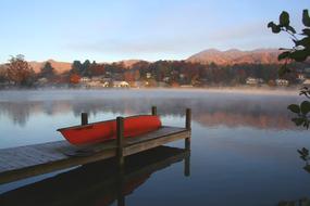 Red boat on the wooden pier in Lake Junaluska, North Carolina, USA, among the buildings and plants