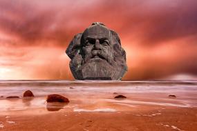 stone head of Marx, beach, pink sky