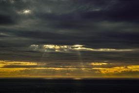 sunbeams behind dark clouds at sunset