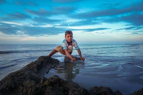 boy on a stone near the sea in indonesia