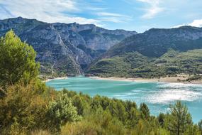 Beautiful landscape of Lac De Sainte-Croix, in sunlight, among the mountains with colorful plants, in France