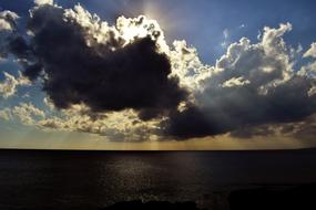 Sunlight in the clouds in the blue sky, above the water