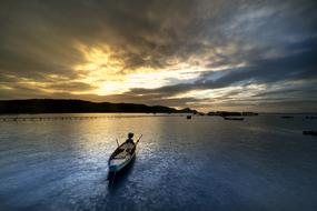 Fishermen on the boat, on the water, near the mountains, at beautiful sunset among the clouds